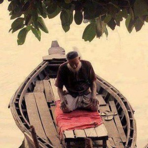 رجل يؤدي الصلاة على قارب.